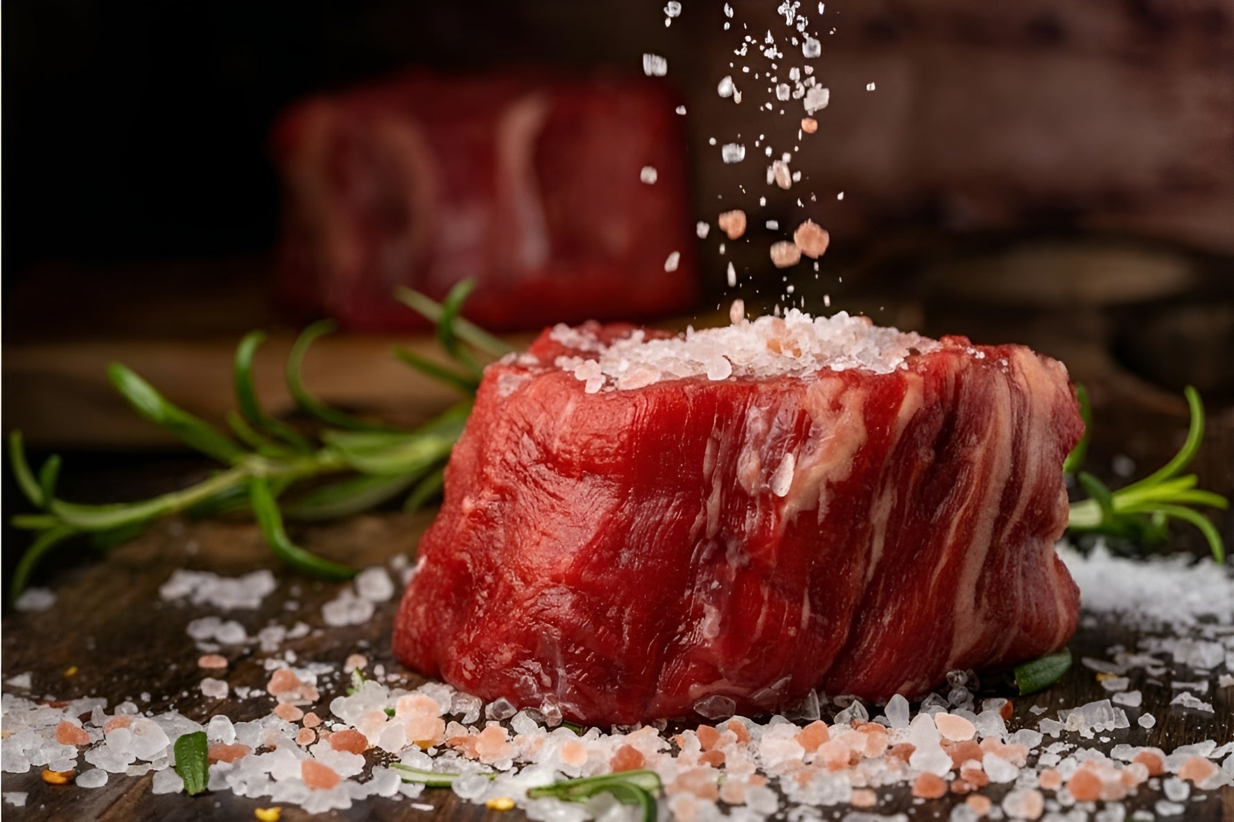 A piece of meat being seasoned with FASL Himalayan pink salt