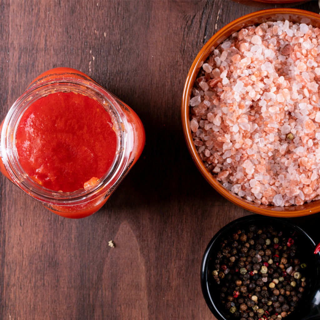 Tomato juice, himalayan pink salt, and peppers in a wooden table